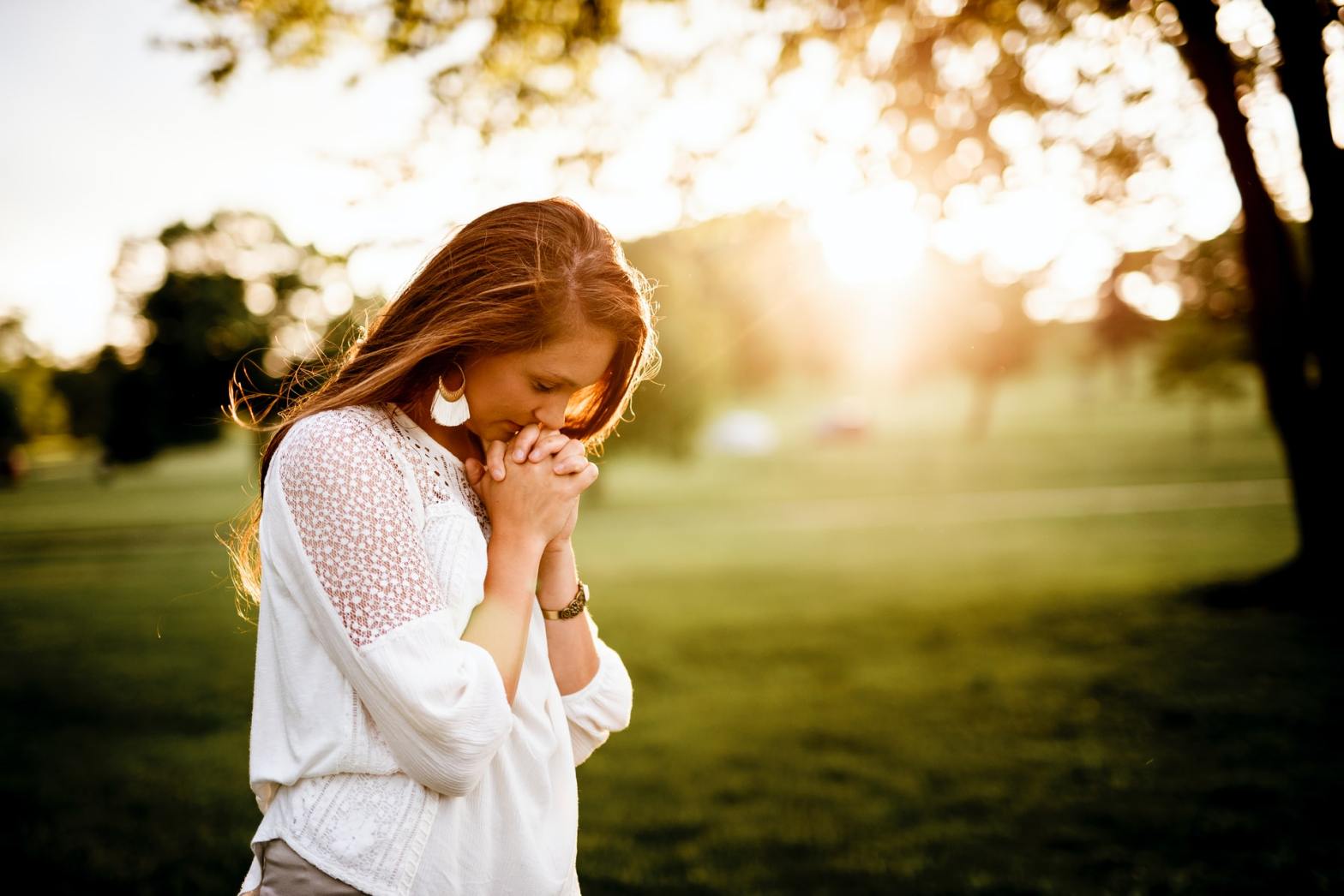 A girl in white praying outside