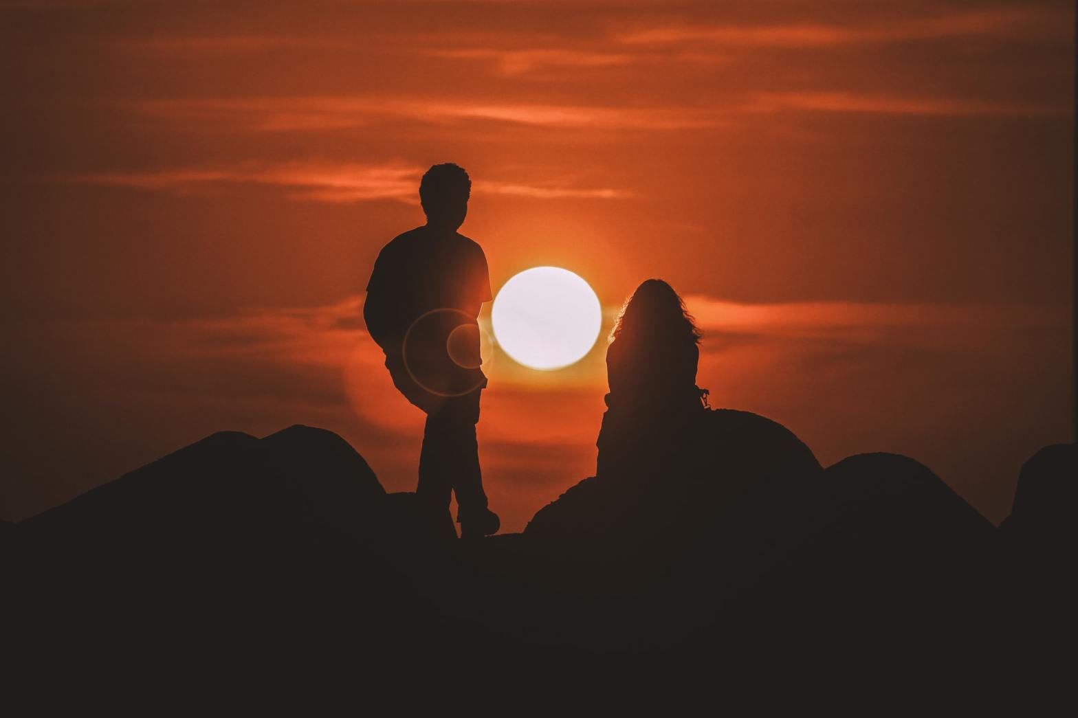 Silhouette of a man and a woman with the sun between them